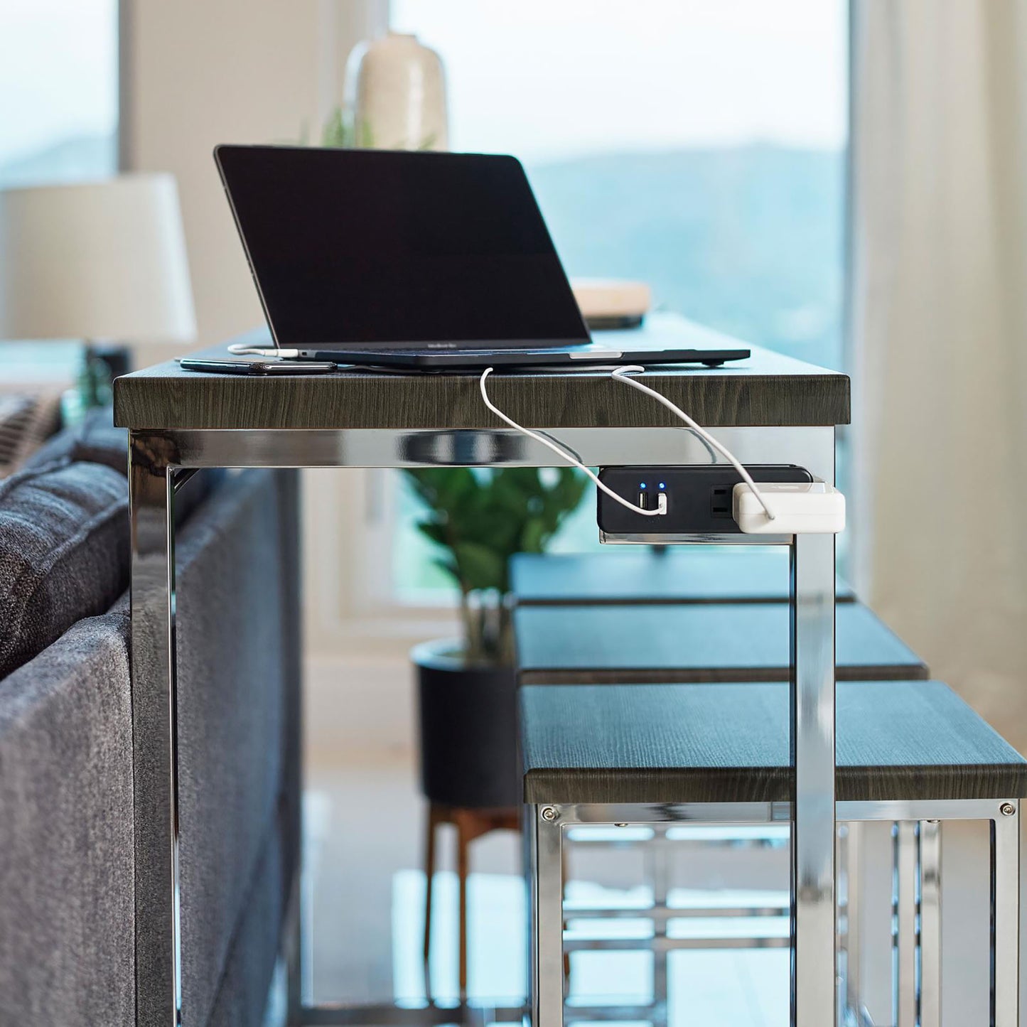 Dark wood and chrome console table with integrated power strip supporting a laptop