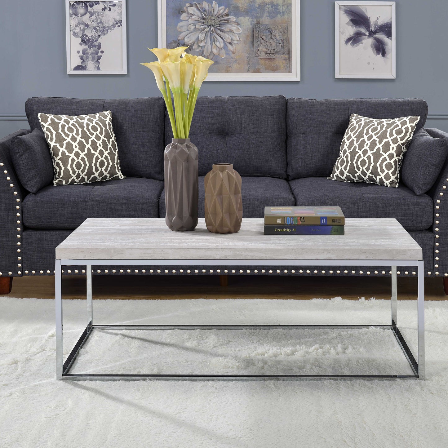 Grey upholstered sofa with decorative nailhead trim and patterned throw pillows