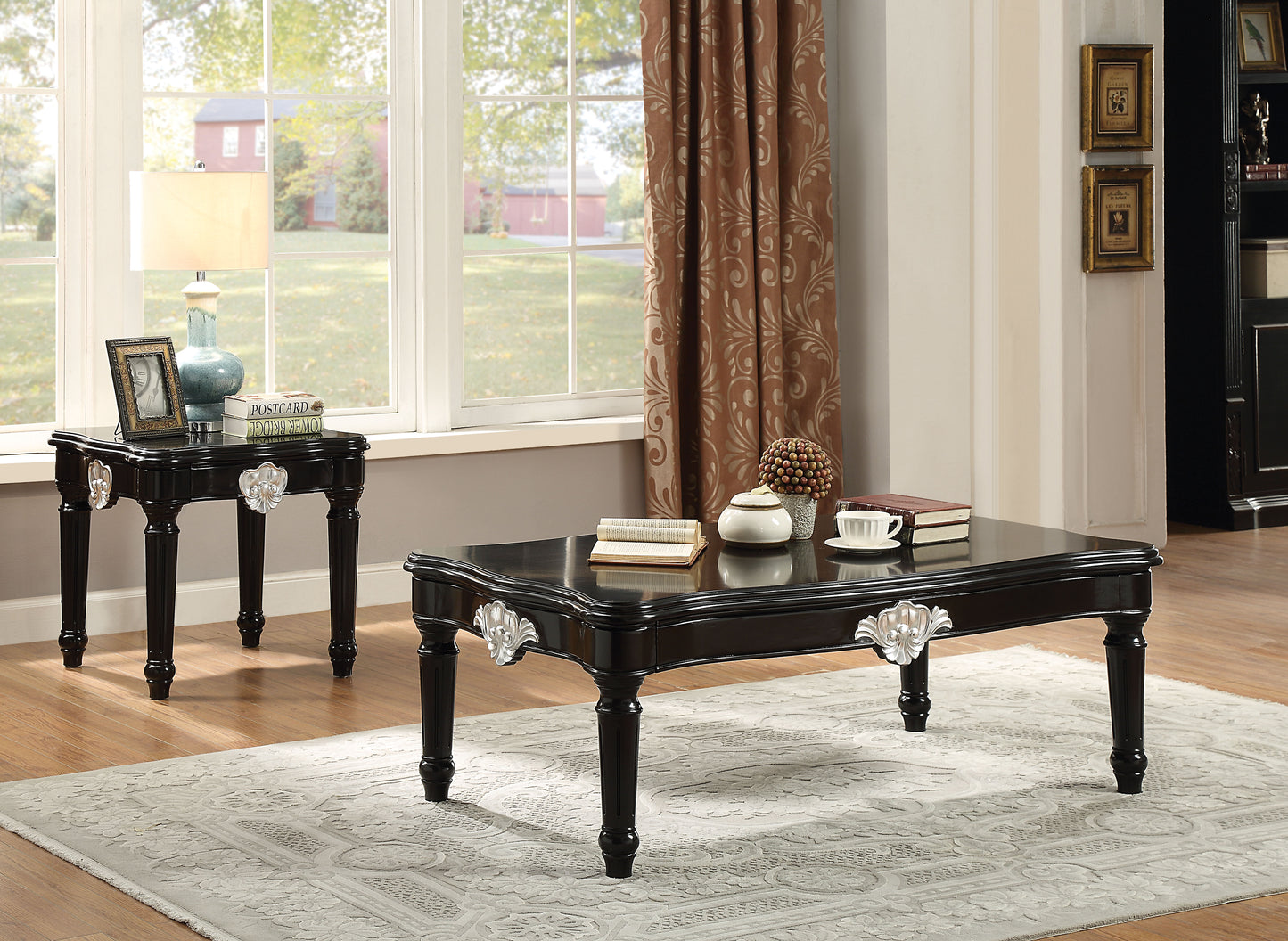 Black ornate coffee table with silver accents featuring books and a teacup