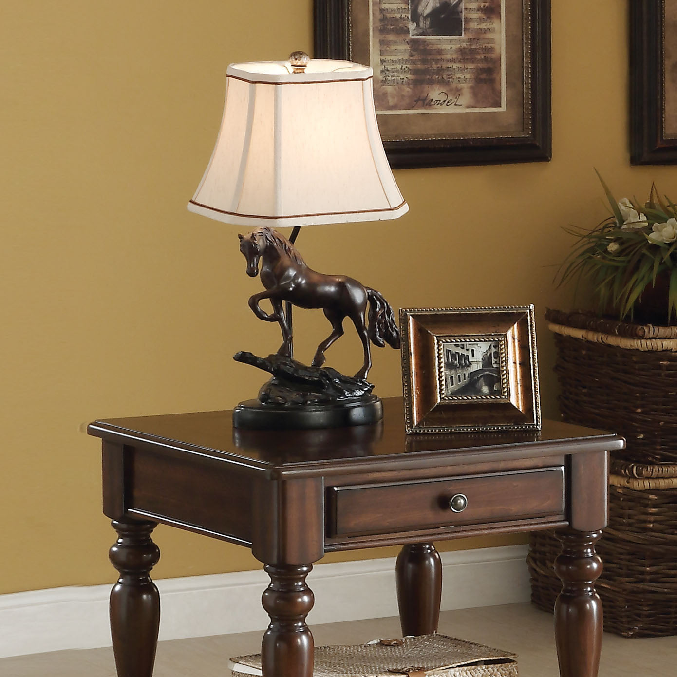 Bronze horse table lamp with a cream shade on a dark wood end table