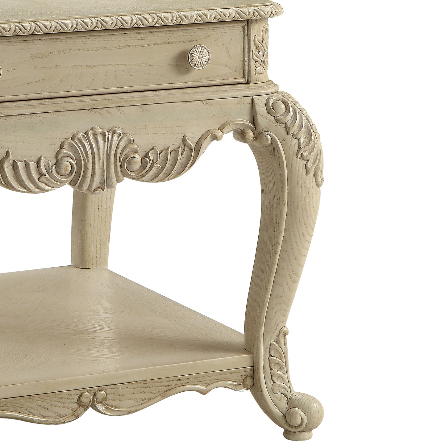 Ornate carved legs of a distressed cream end table with drawer offering vintage charm