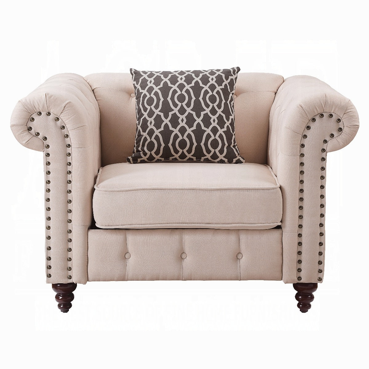 Beige fabric chesterfield armchair with dark geometric pillow and bronze nailhead trim