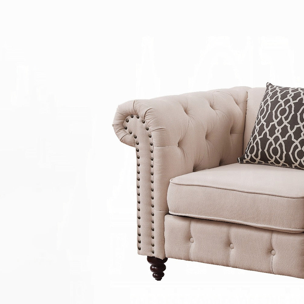 Beige upholstered chesterfield sofa with tufted back and decorative nailhead trim