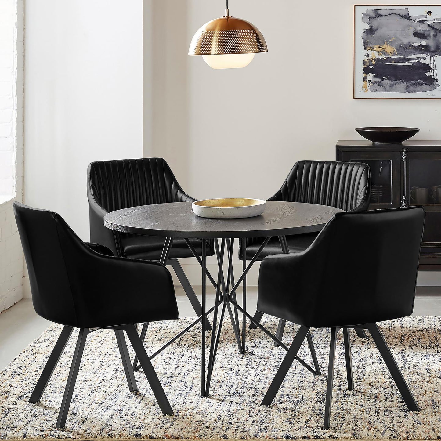 Four black velvet dining chairs with channel tufting around a round black wood table