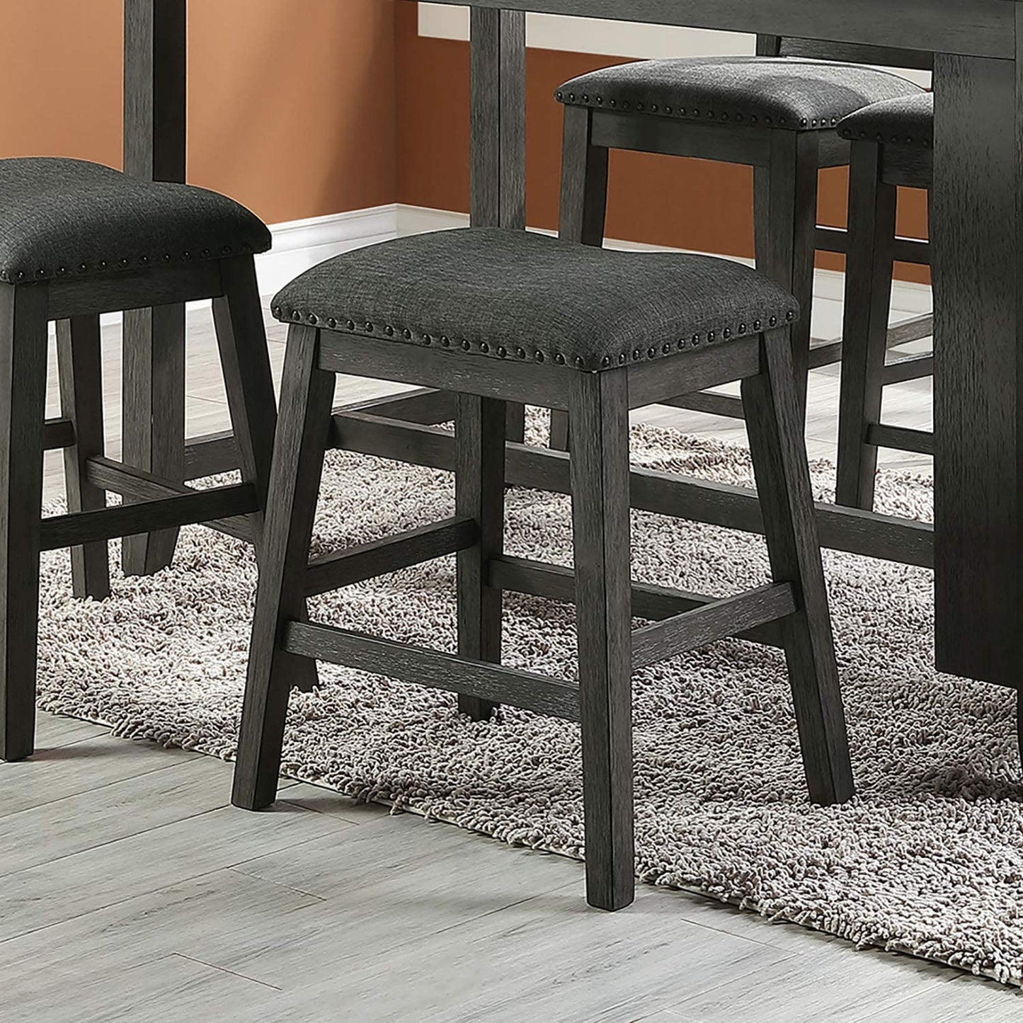 Dark gray upholstered bar stool with nailhead trim and distressed wood frame
