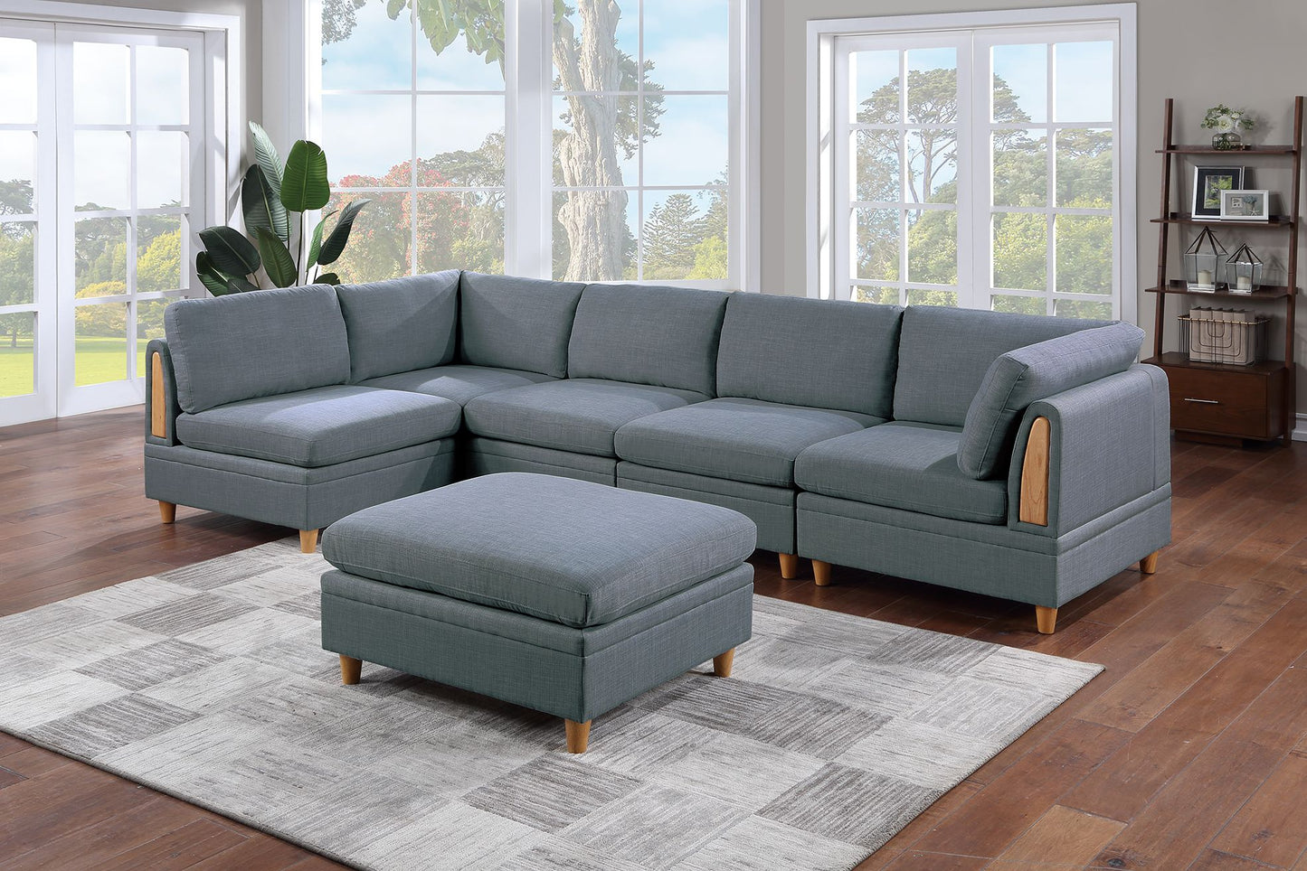 Gray fabric sectional sofa with wooden arm accents and matching ottoman on a geometric rug