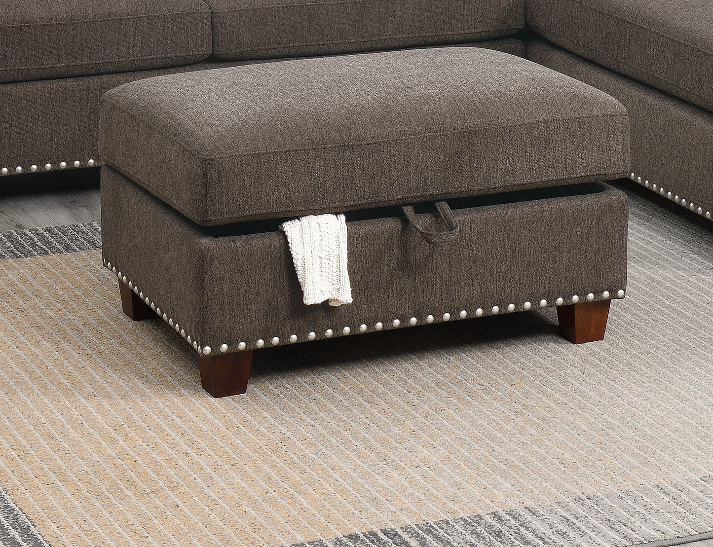 Tufted brown fabric storage ottoman with silver nailhead trim and wooden legs