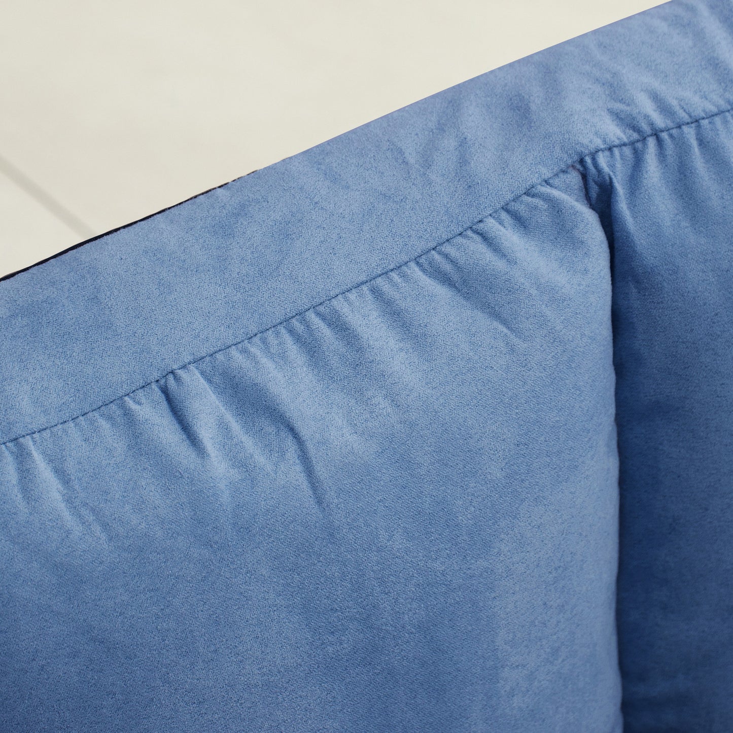 Closeup of light blue denim fabric with detailed stitching and pleats