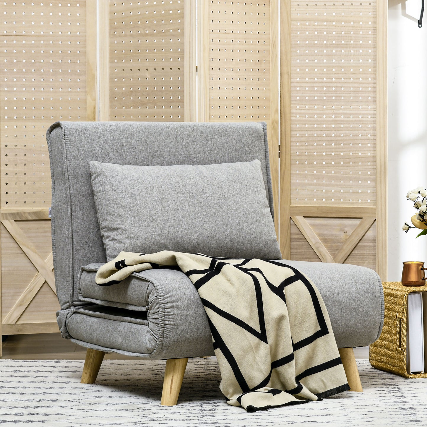 Gray upholstered convertible sofa bed with a black and cream geometric throw blanket
