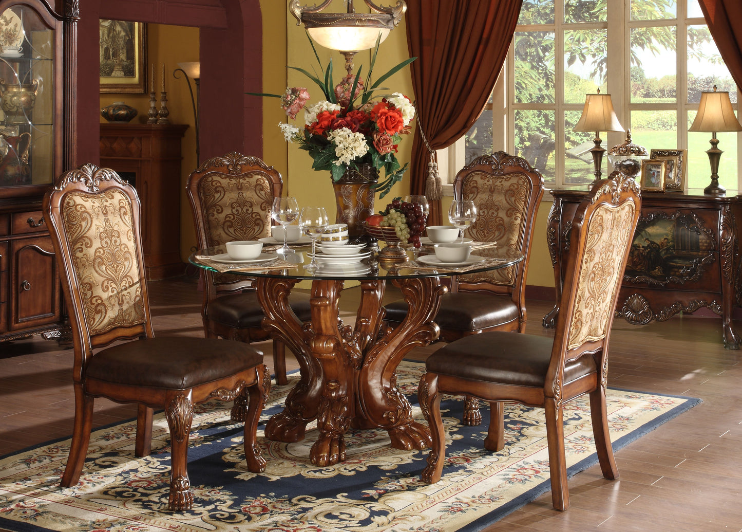 Round glass dining table with ornate wooden base and matching carved chairs set for four