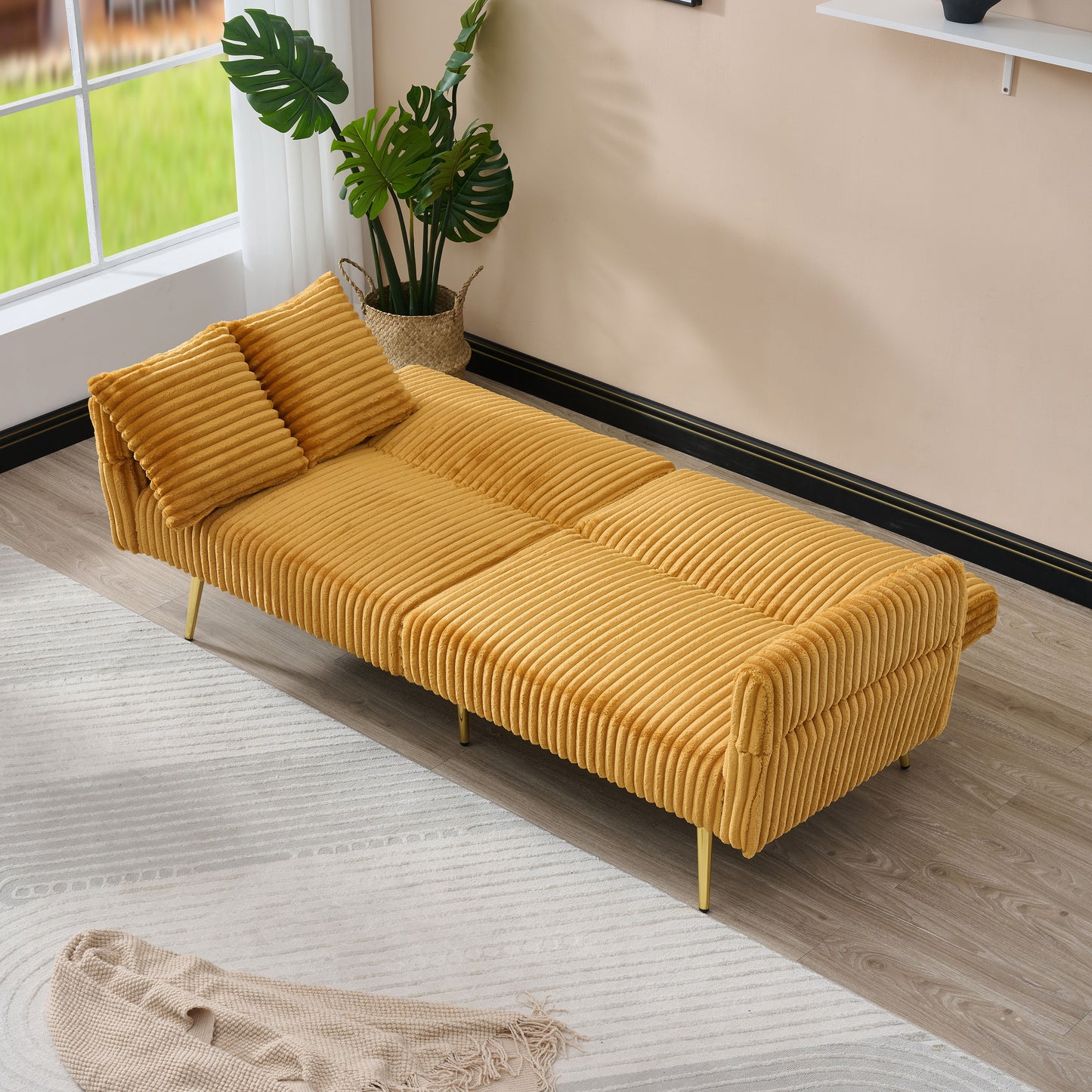 Yellow corduroy futon sofa with plush cushions and gold legs in a living room setting