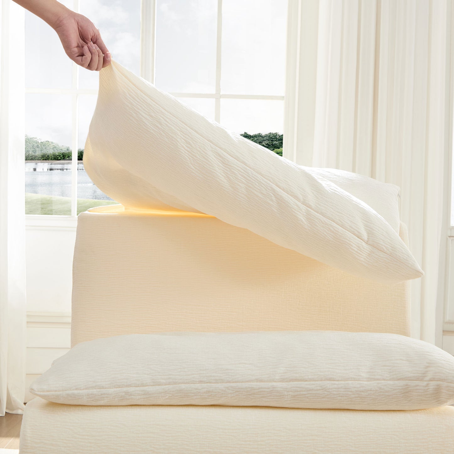 Cream textured pillowcase being placed on a plush cream sofa for a cozy living room aesthetic