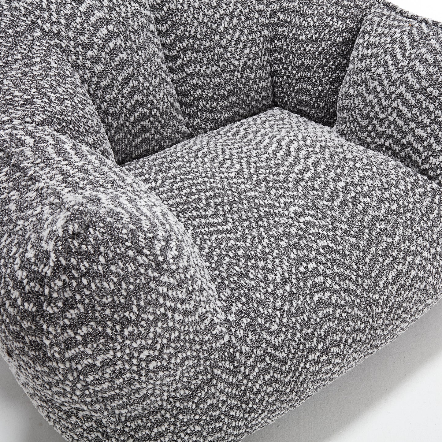 Closeup of a grey and white textured fabric armchair cushion with a boucl weave