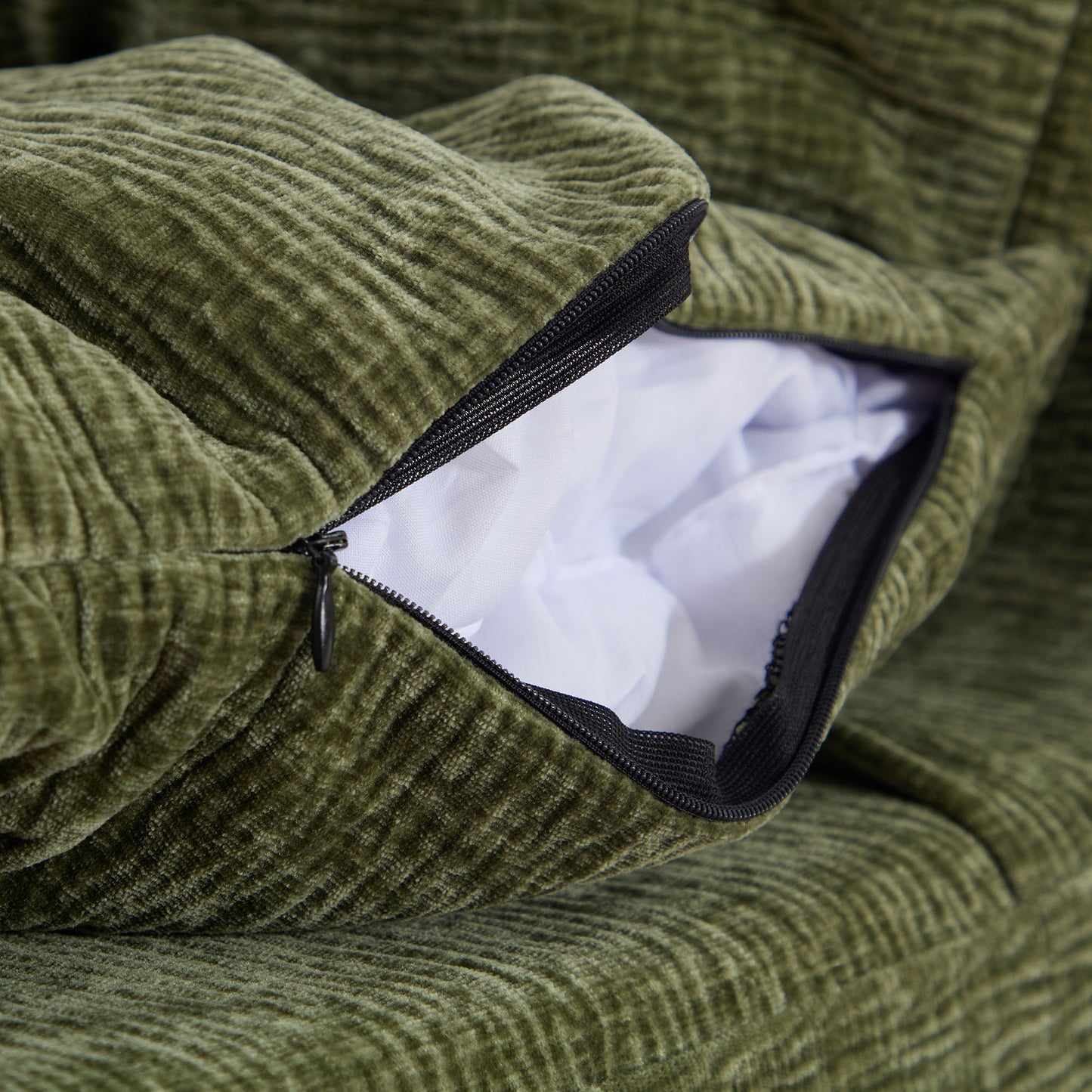 Closeup of a textured olive green corduroy bean bag zipper partially open revealing white inner liner