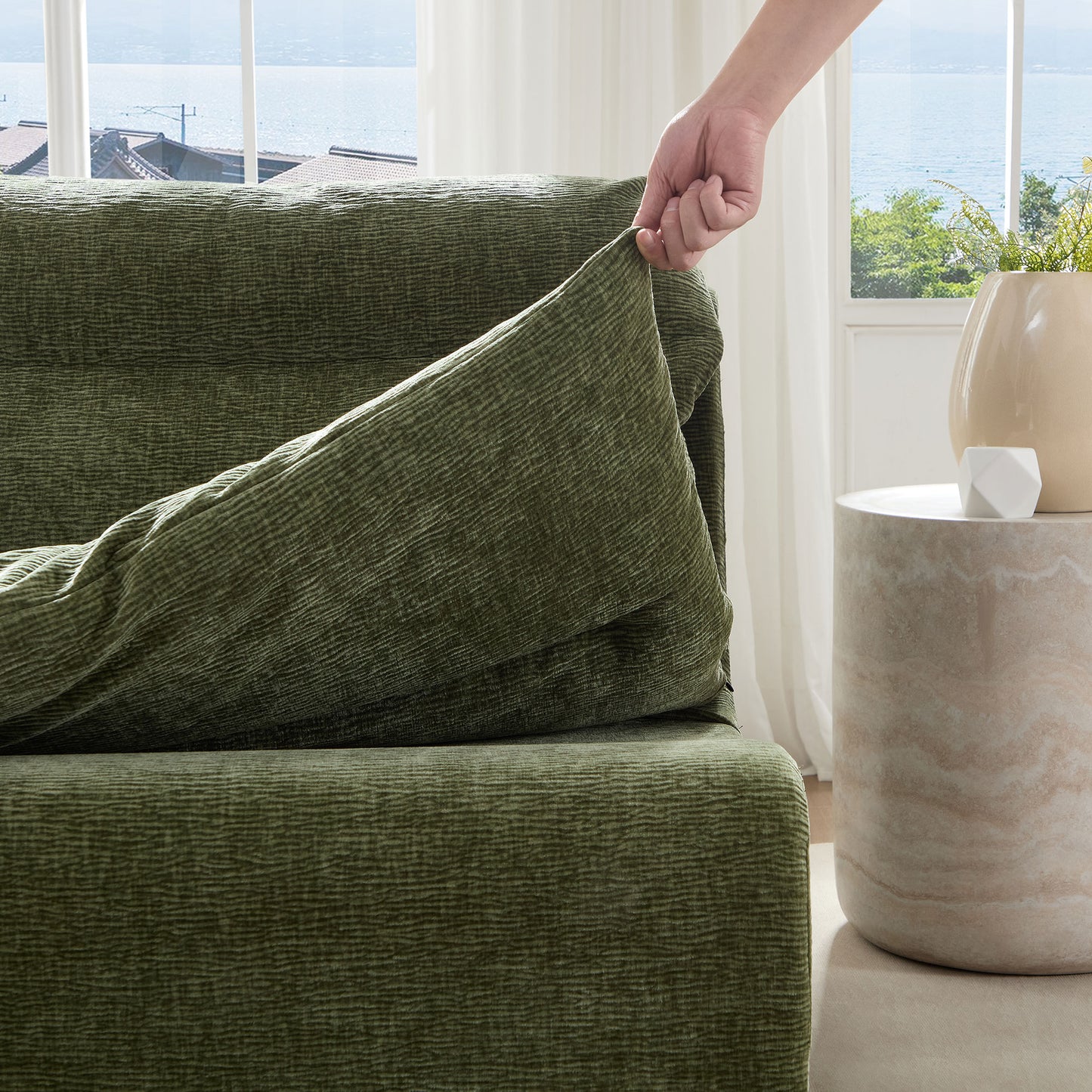 Green textured sofa slipcover being applied offering a cozy and protective furniture upgrade