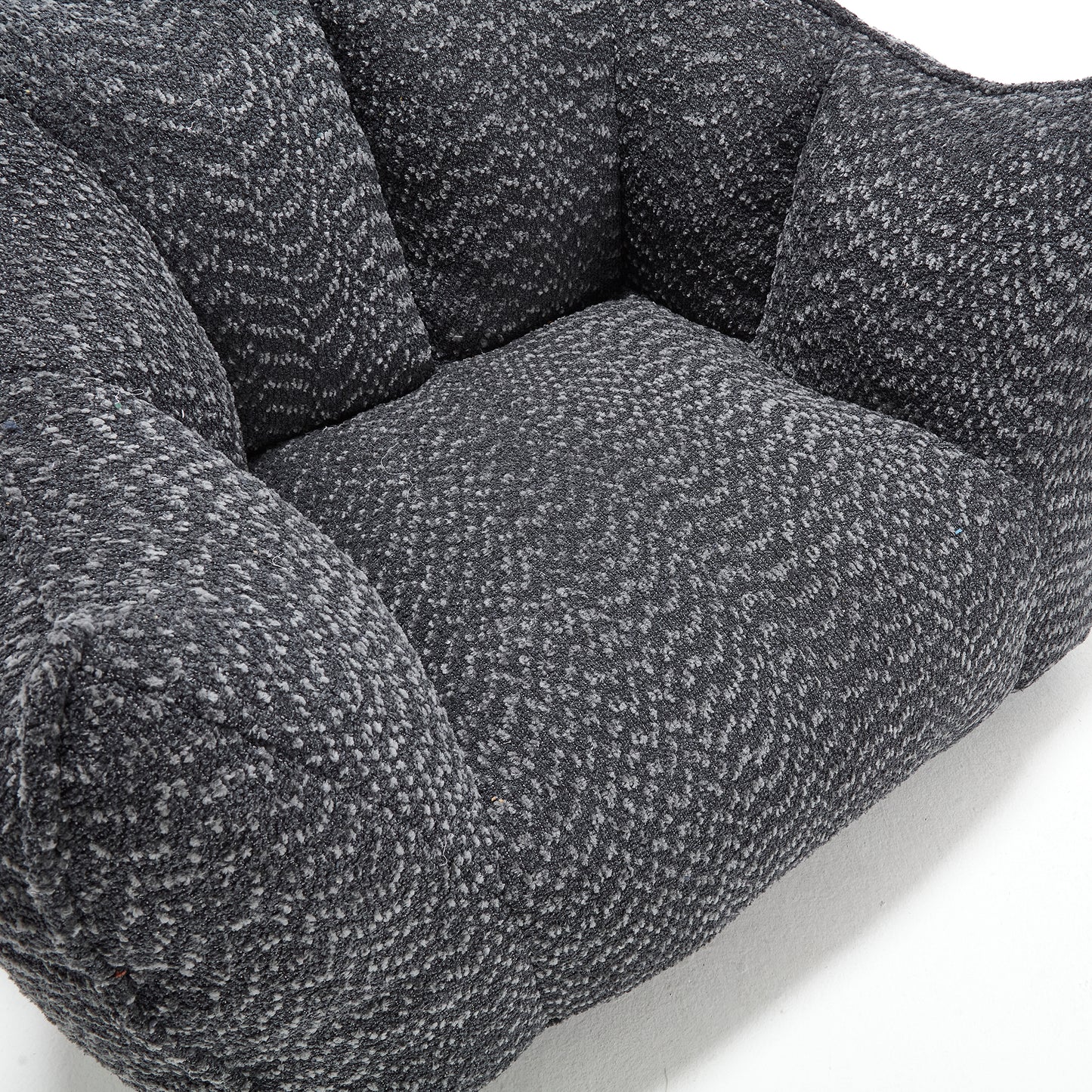 Closeup of a textured dark grey armchair with plush cushioning perfect for modern living rooms
