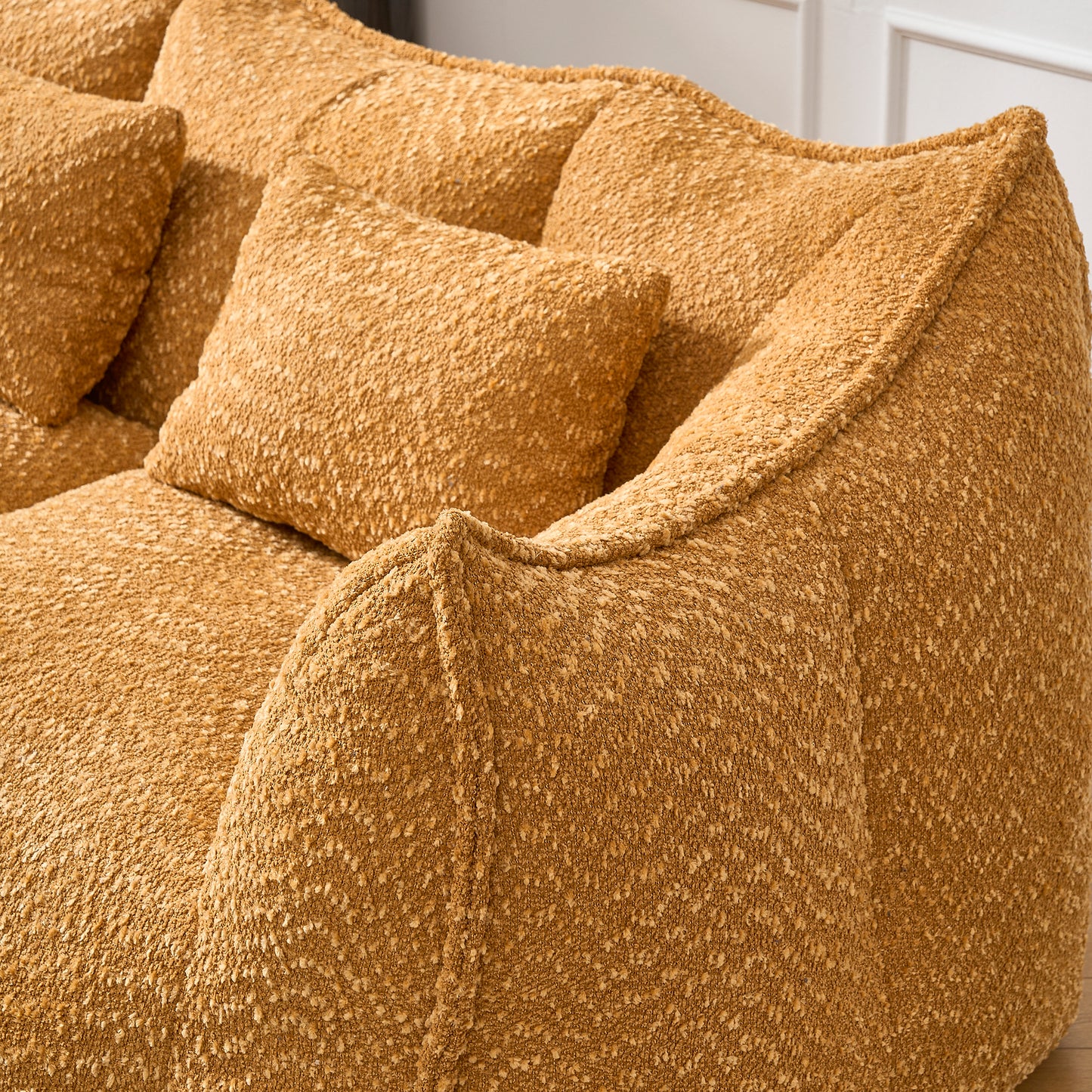 Textured ochre boucle fabric sofa with plush throw pillows for cozy living room comfort