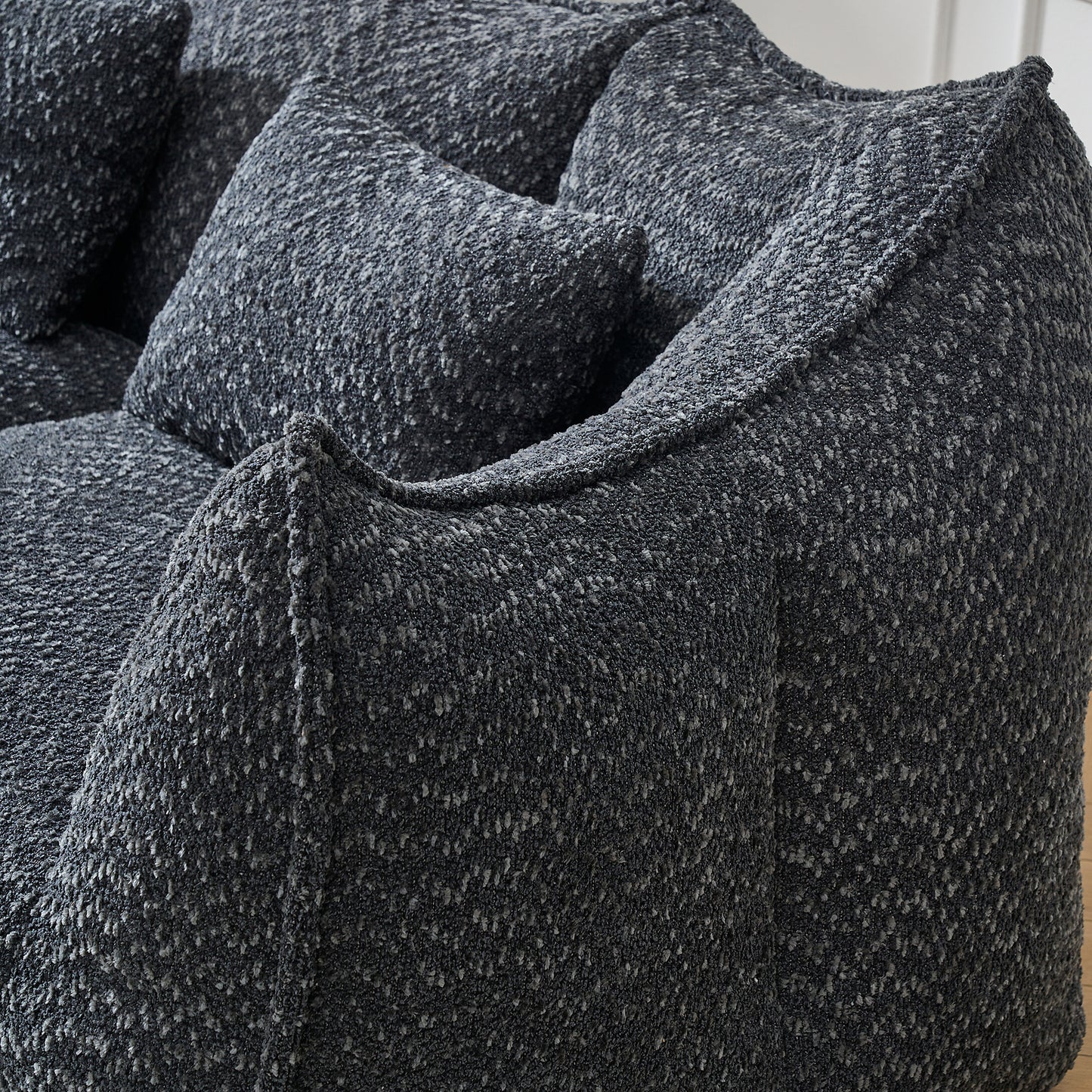 Closeup of a textured charcoal boucl sofa with plush throw pillows offering a cozy seating experience