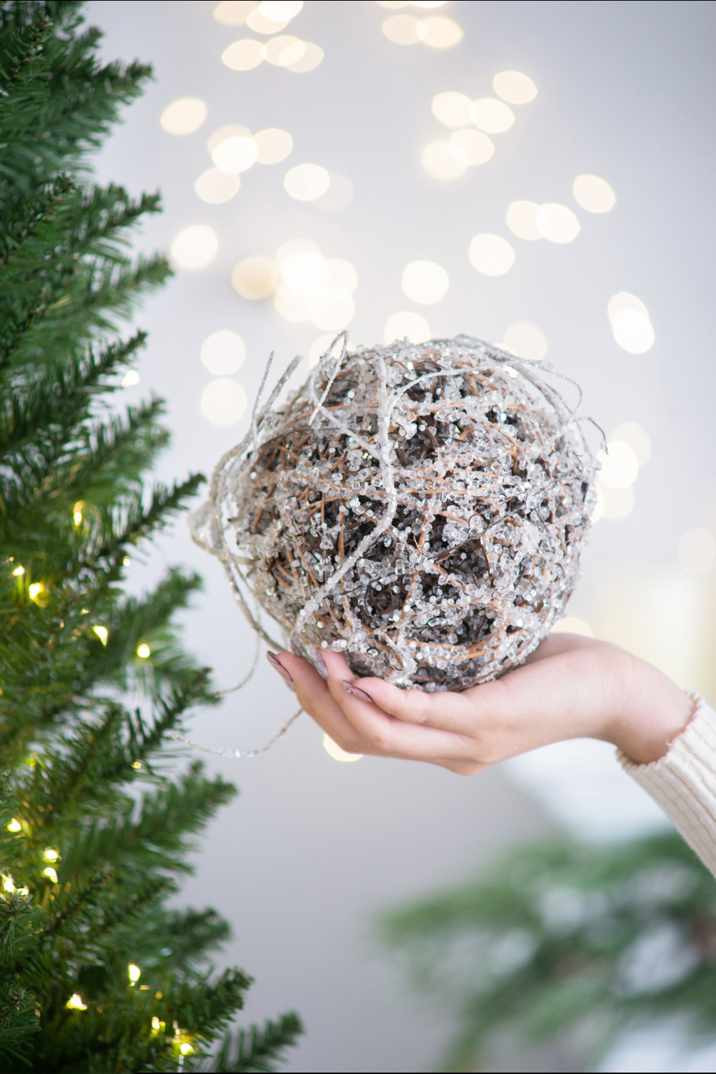 Hand holding a sparkling silver twig ball Christmas ornament
