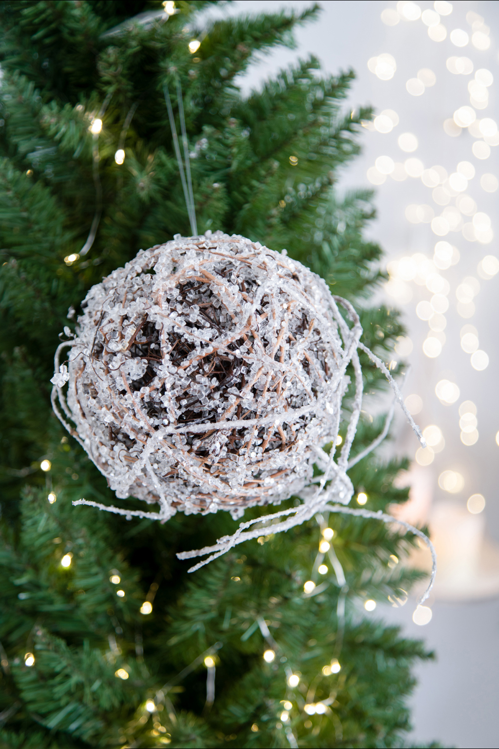 Textured orb ornament with glittery white accents hanging on a Christmas tree