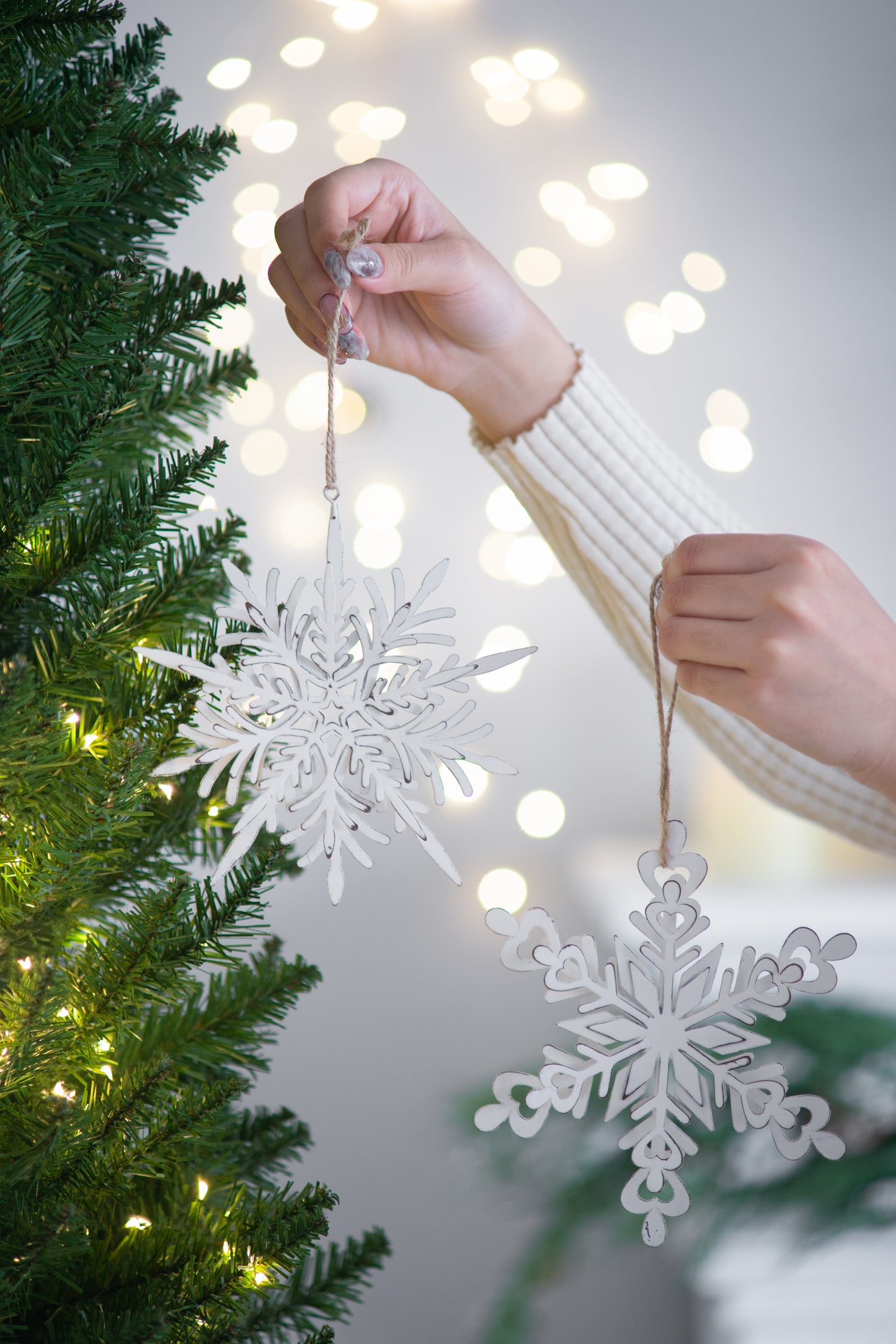 White lasercut snowflake ornament hanging on a Christmas tree