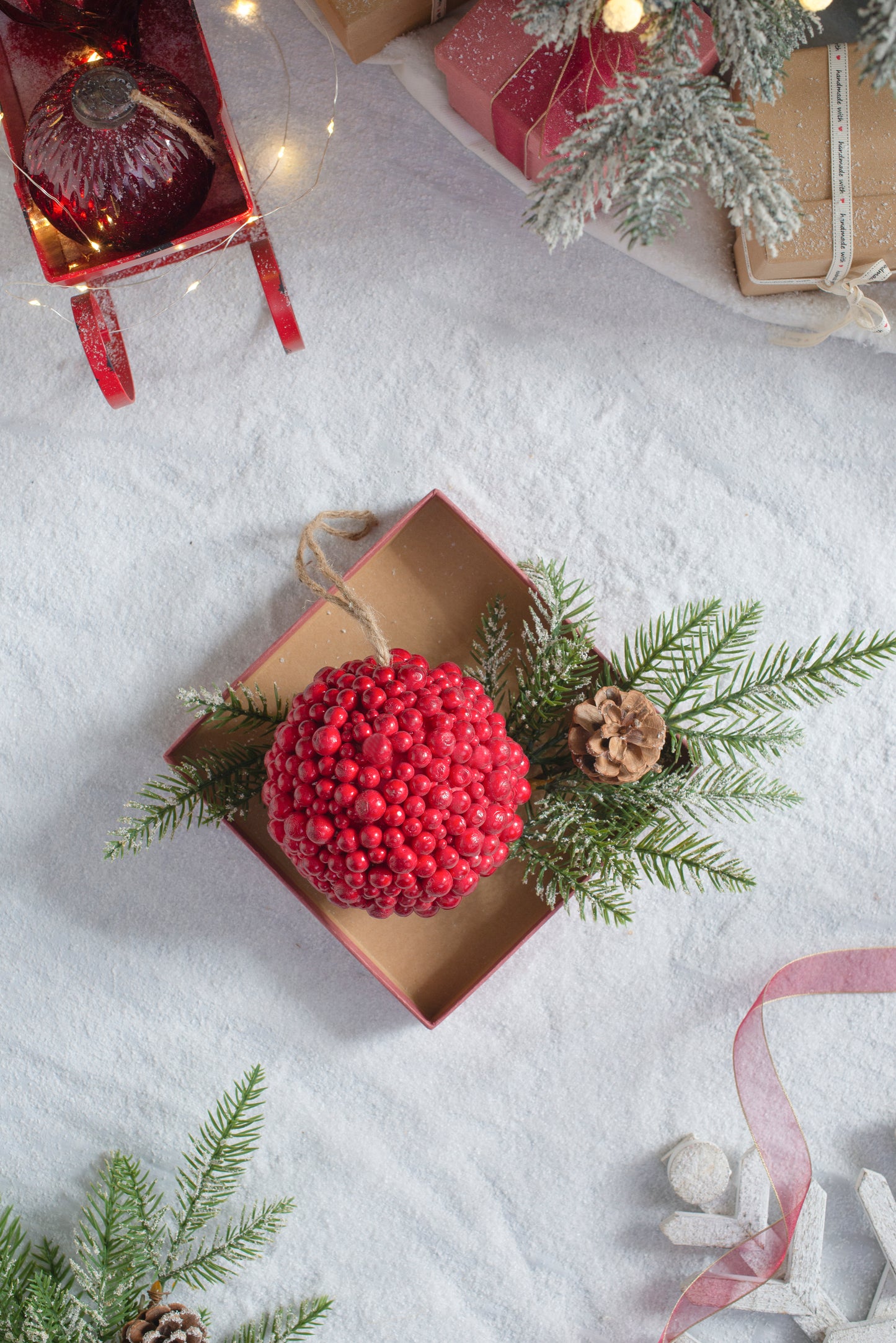Red berry bauble Christmas ornament with pine sprigs in an open gift box
