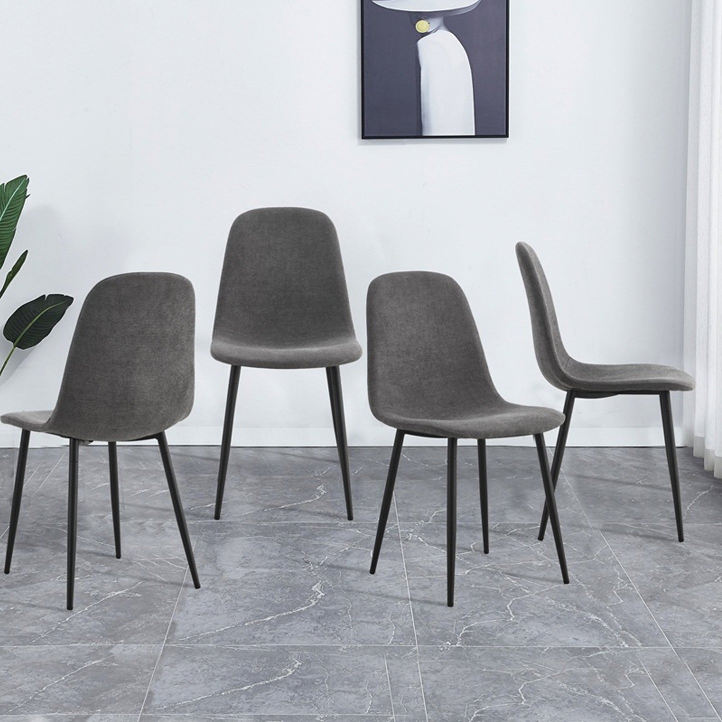 Four modern grey fabric dining chairs with black metal legs arranged around a table