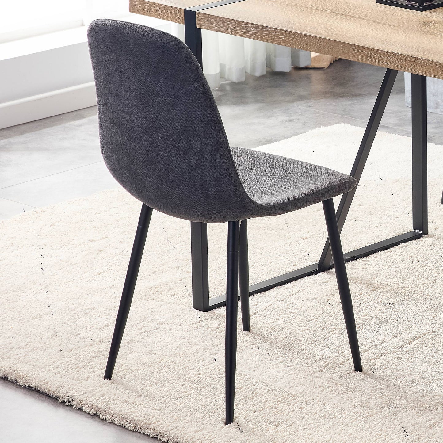 Dark gray upholstered dining chair with black metal legs on a cream rug