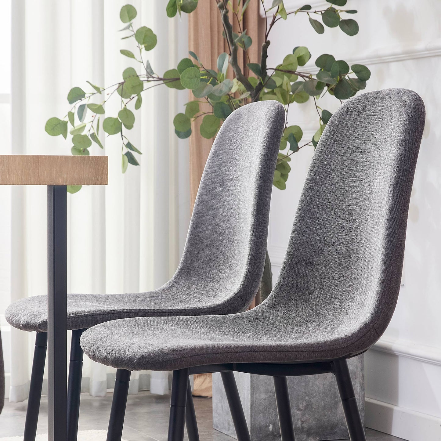 Two upholstered gray dining chairs with black legs in a modern setting