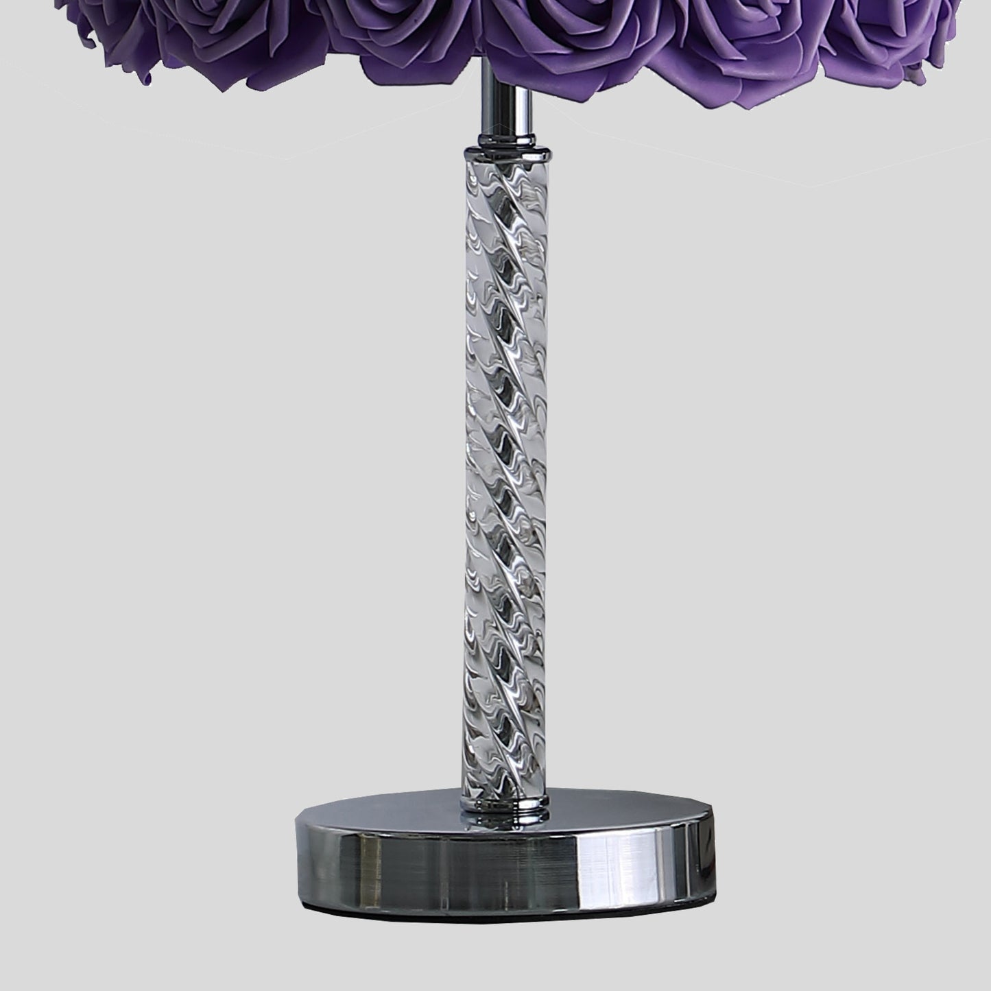 Closeup of a chrome base with a twisted silver stem supporting purple roses