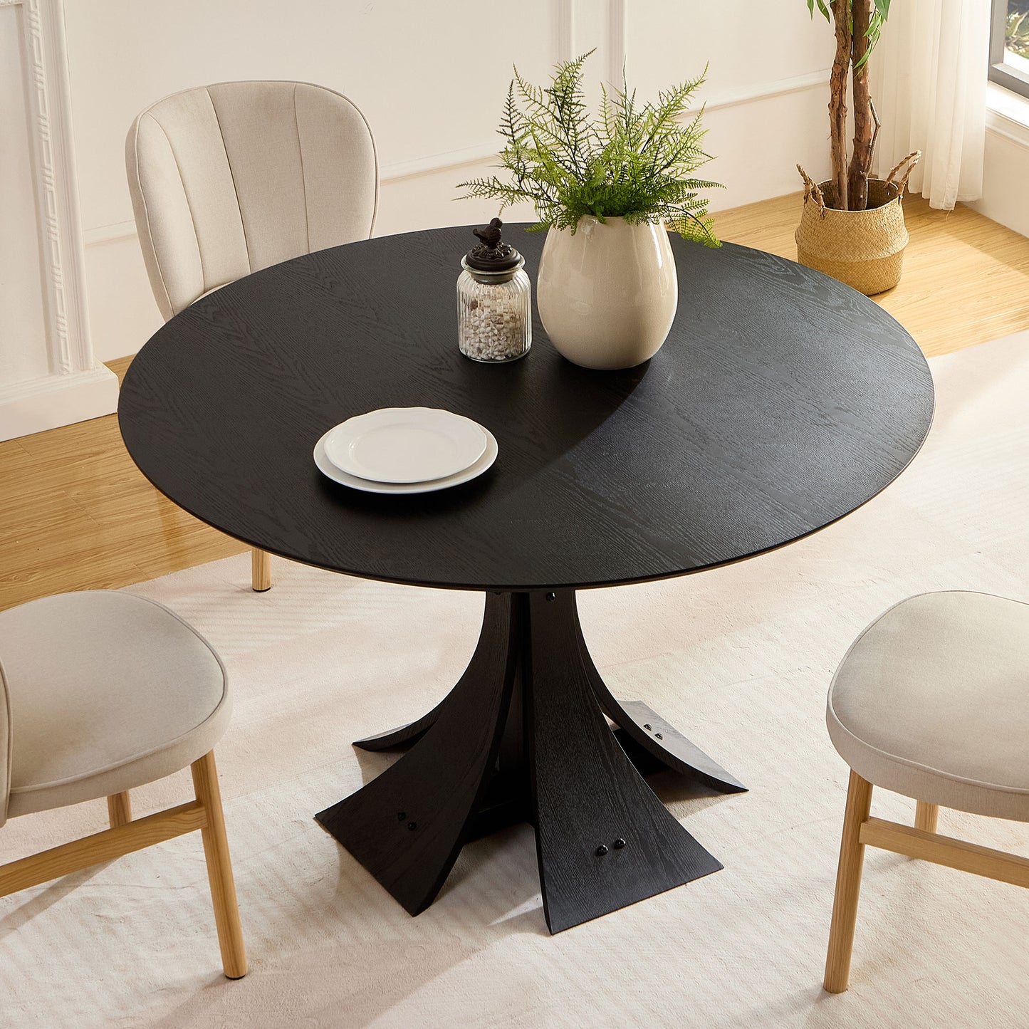 Round black wood dining table with sculptural base and light grey chairs
