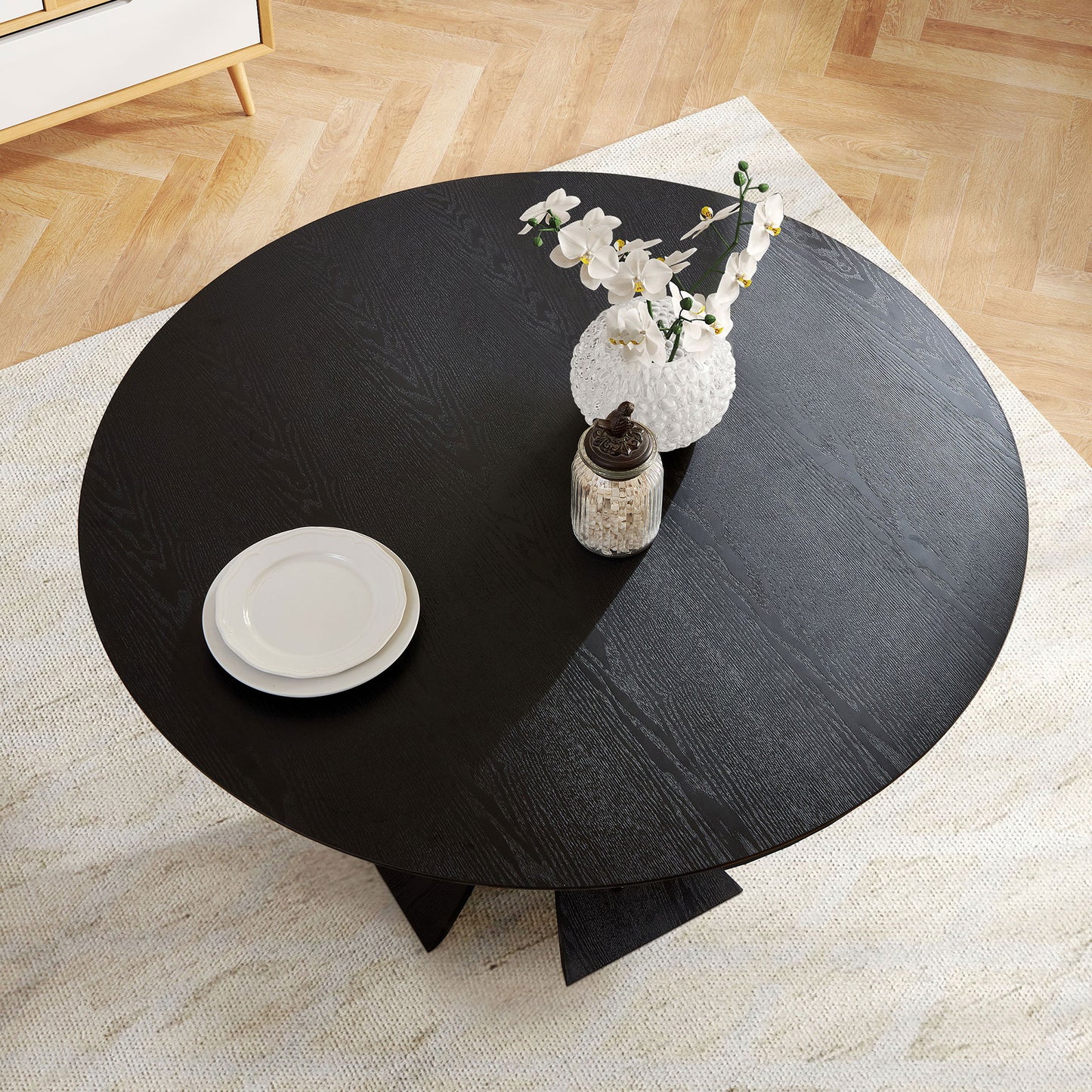 Modern black round dining table with wood grain detail seats four