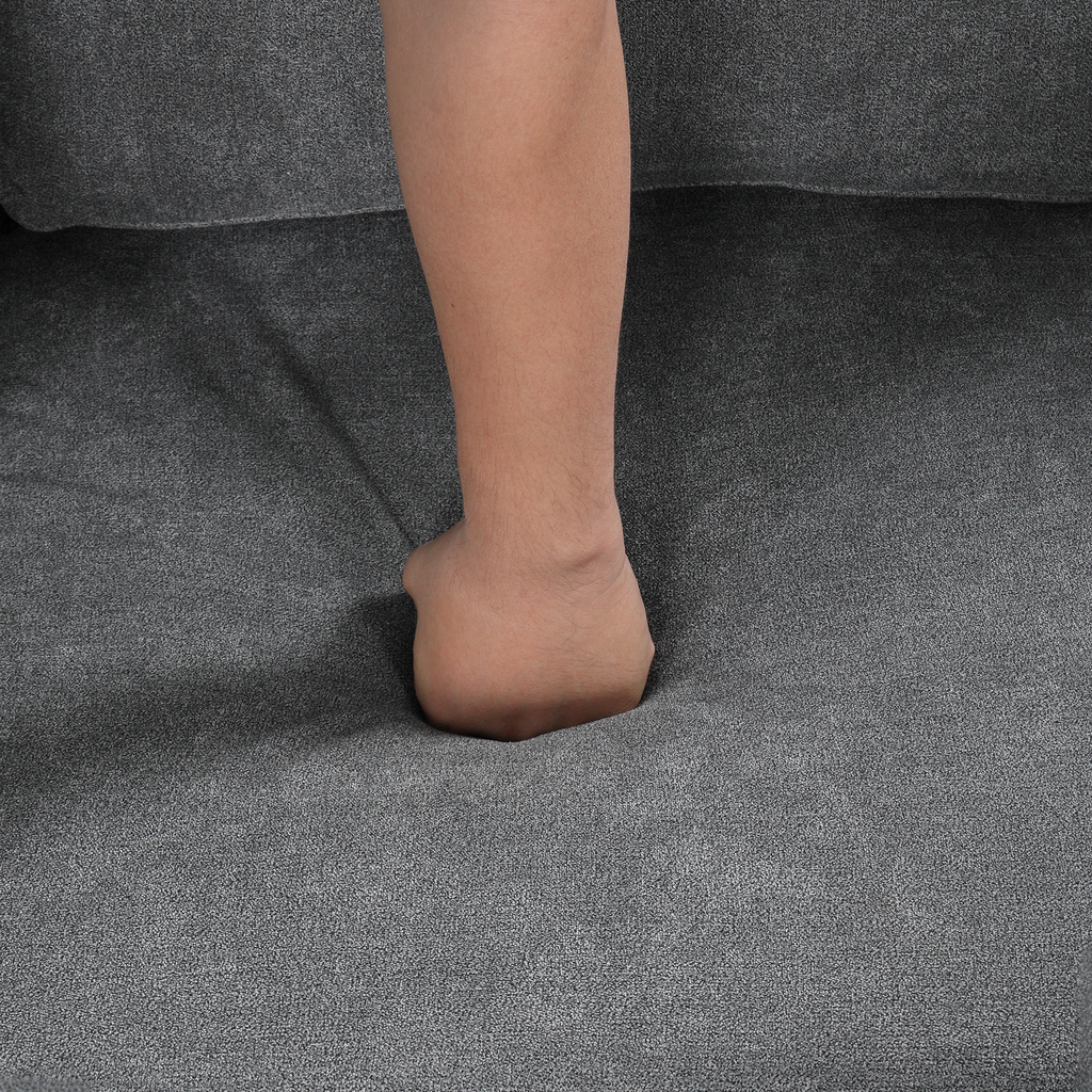 A hand pressing into plush grey sofa cushioning demonstrating comfort and support