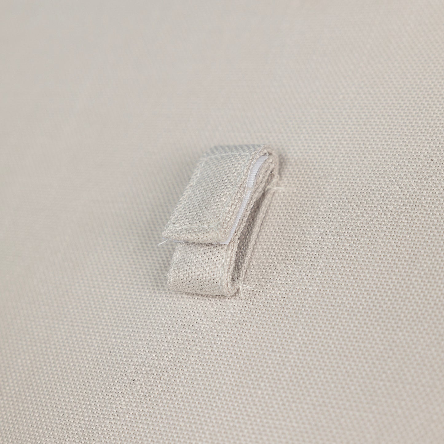 Closeup of beige canvas fabric with a folded fabric loop detail