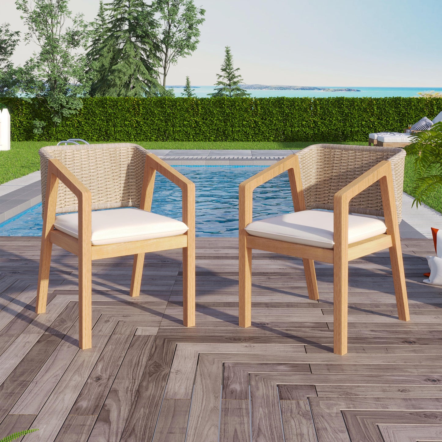 Two wicker outdoor chairs with white cushions on a wooden deck by a pool