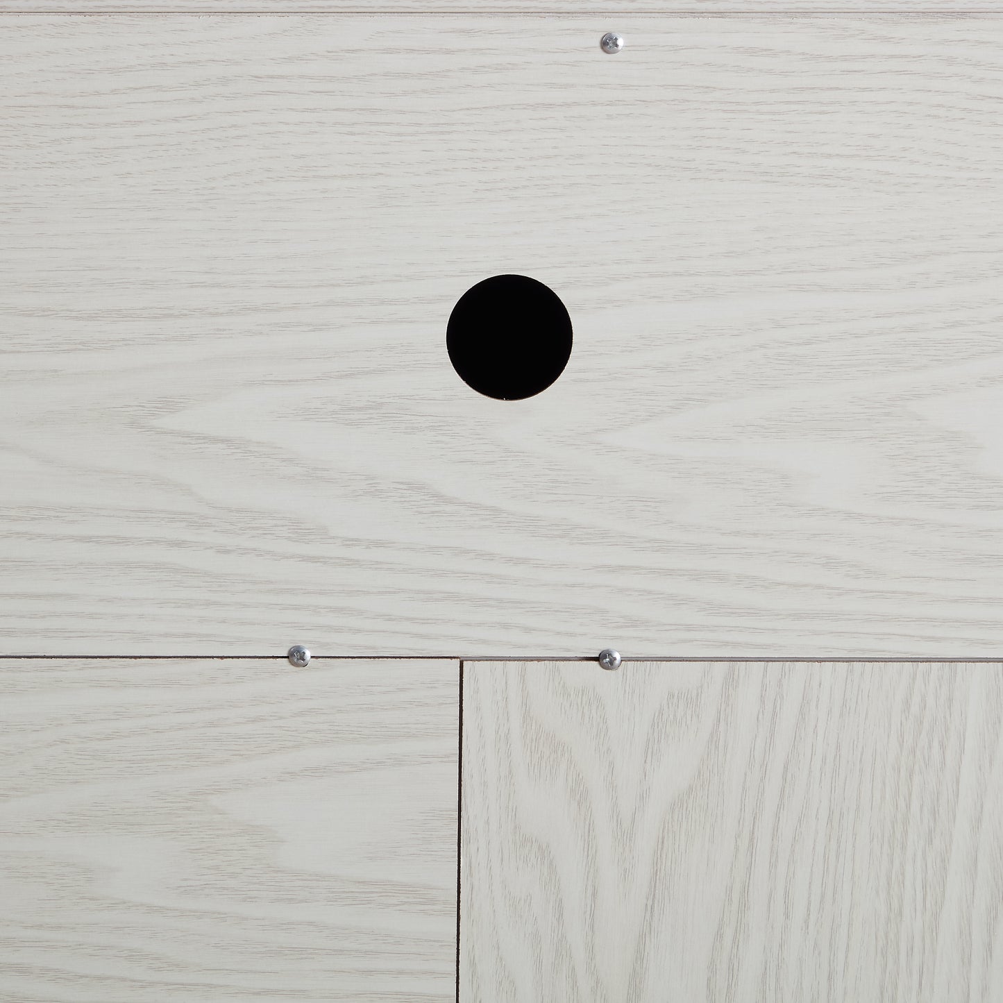 Closeup of light oak wood veneer panel with cable management hole
