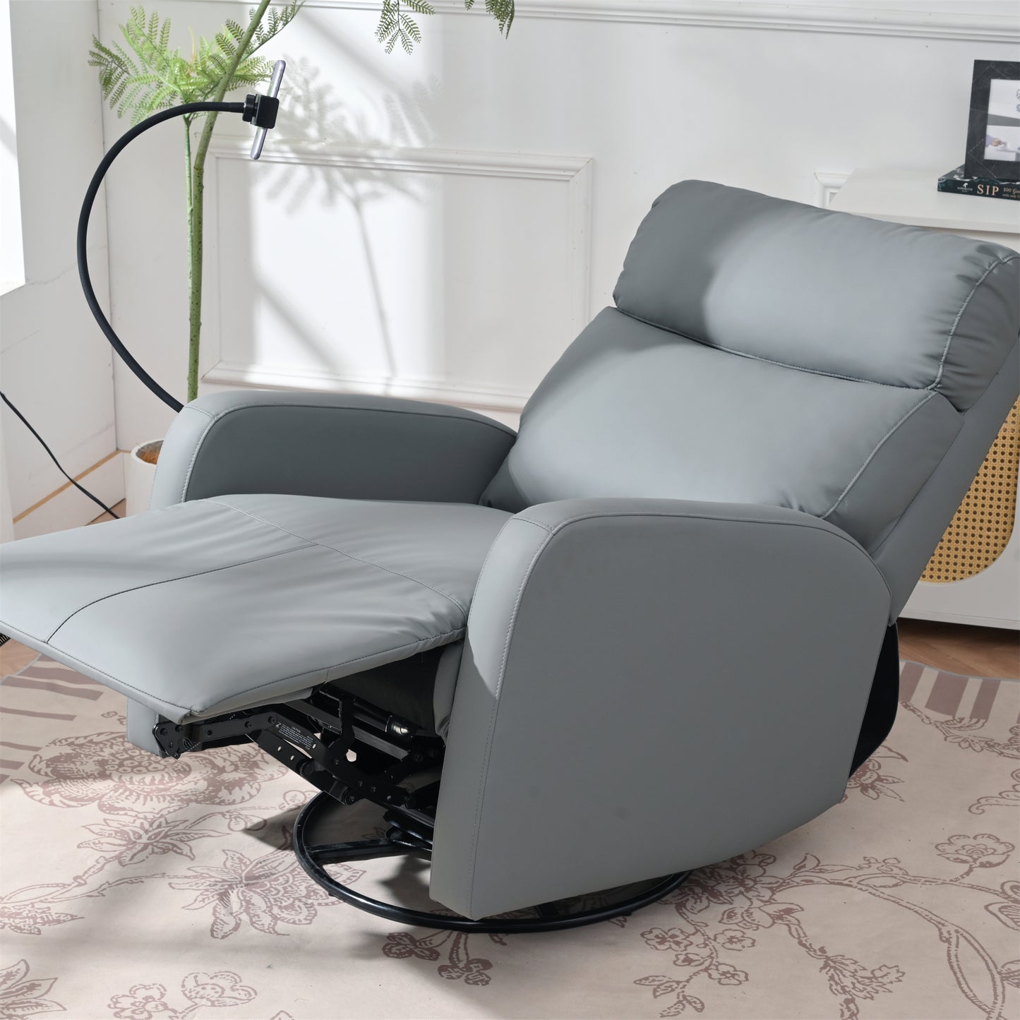 Grey upholstered swivel recliner chair with padded footrest and adjustable headrest
