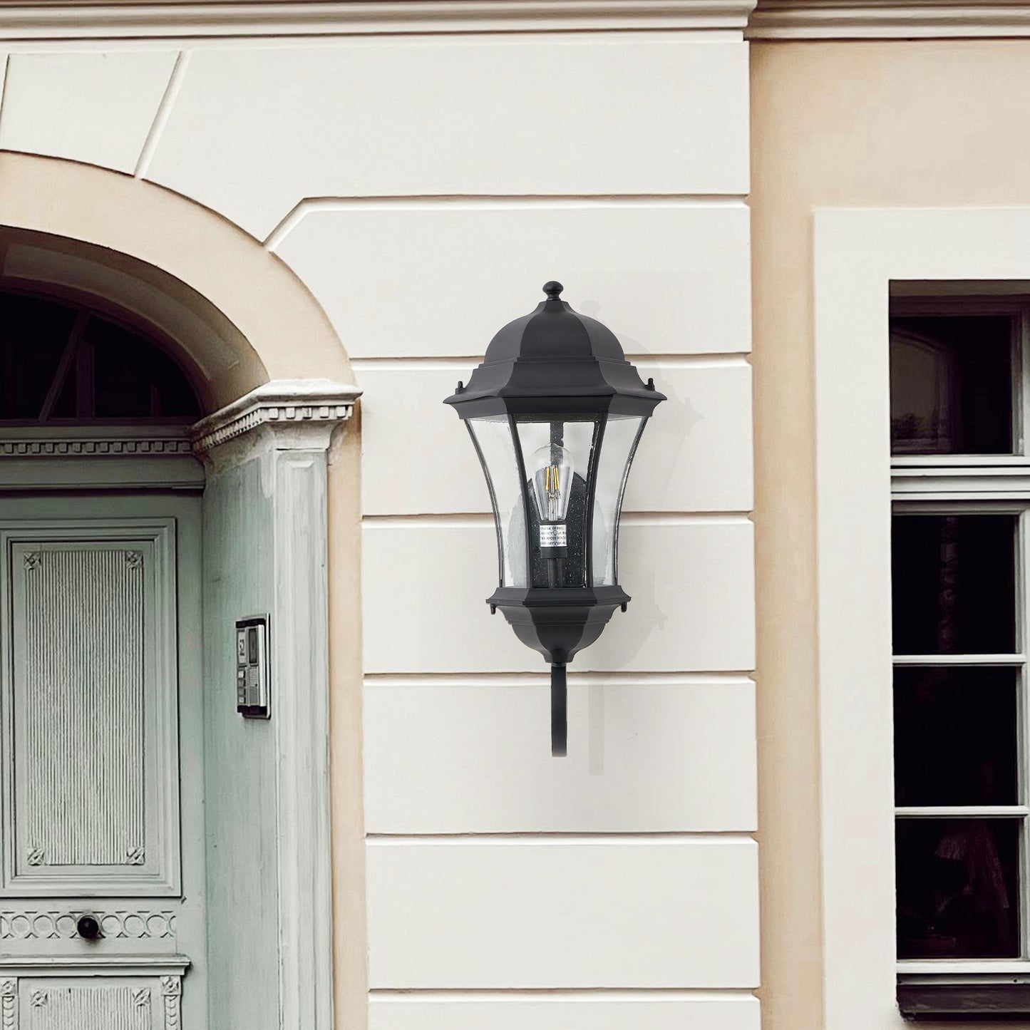 Black traditional outdoor wall lantern with clear seeded glass and visible filament bulb