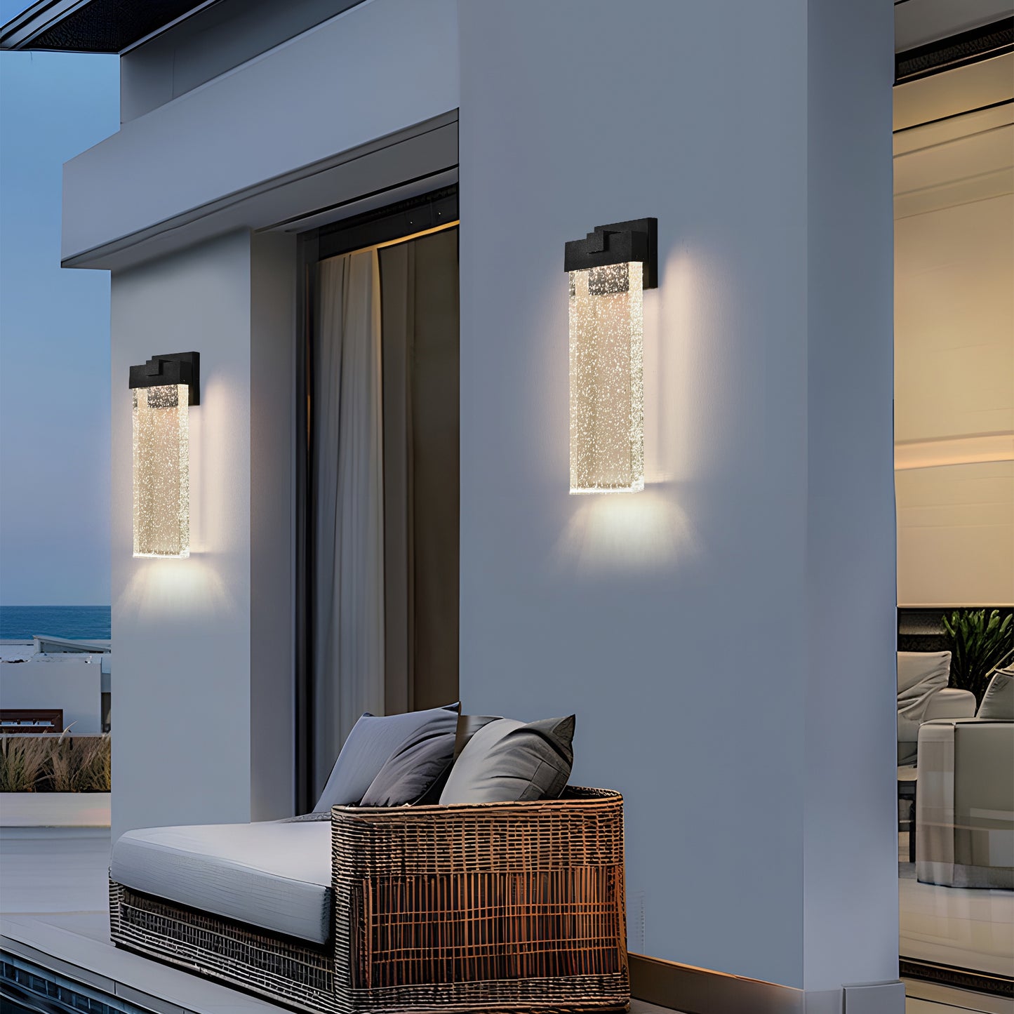 Modern black outdoor wall light with clear bubble glass cylinder illuminating patio