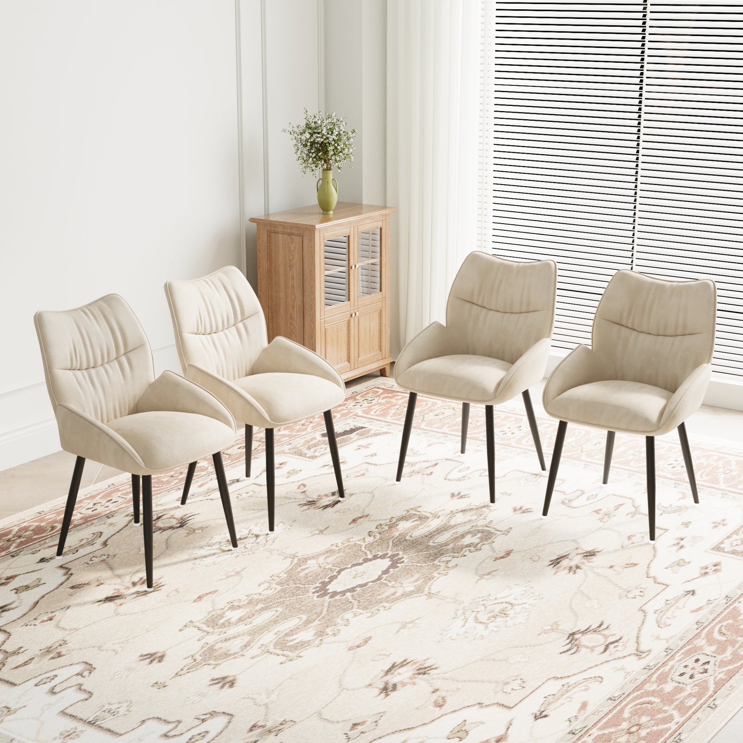 Four cream velvet dining chairs with dark tapered legs arranged on a patterned rug