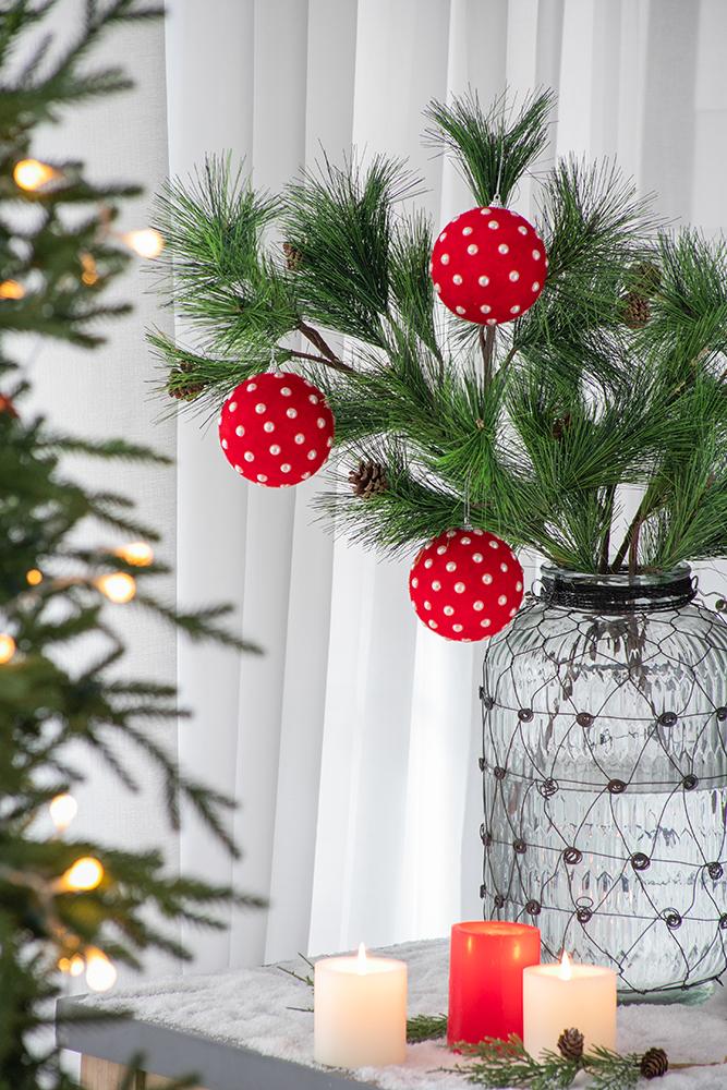 Red polka dot Christmas ornaments hanging on pine branches