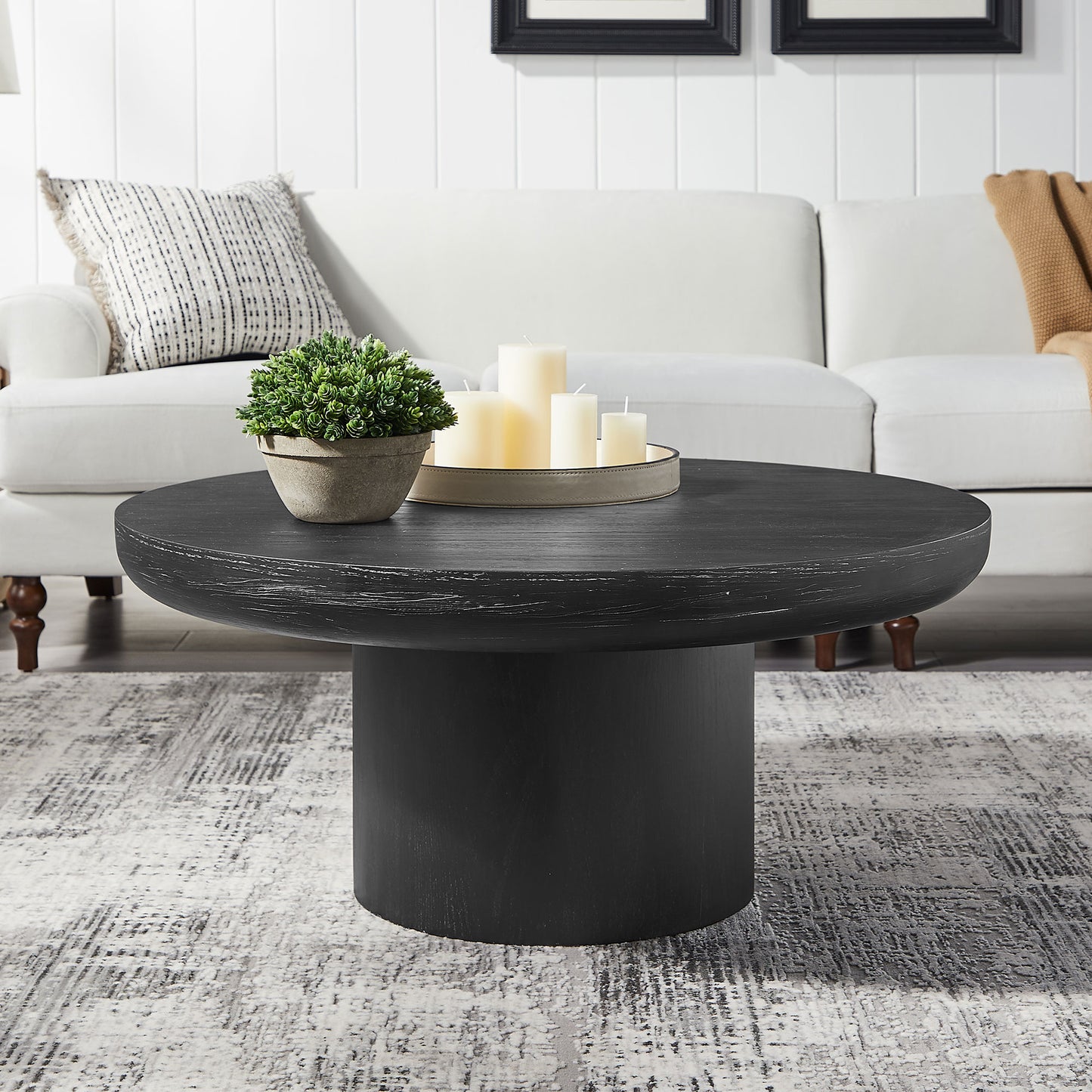 Black round wood coffee table with a distressed finish and cylindrical base
