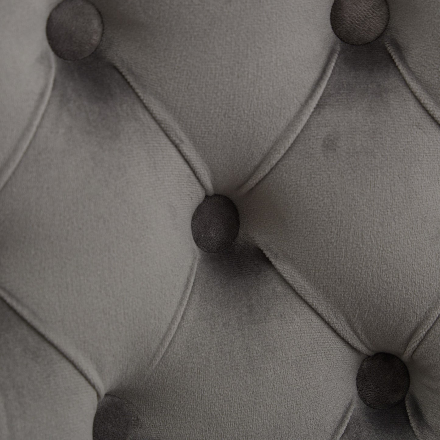 Closeup of gray velvet fabric with deep button tufting detail for upholstery