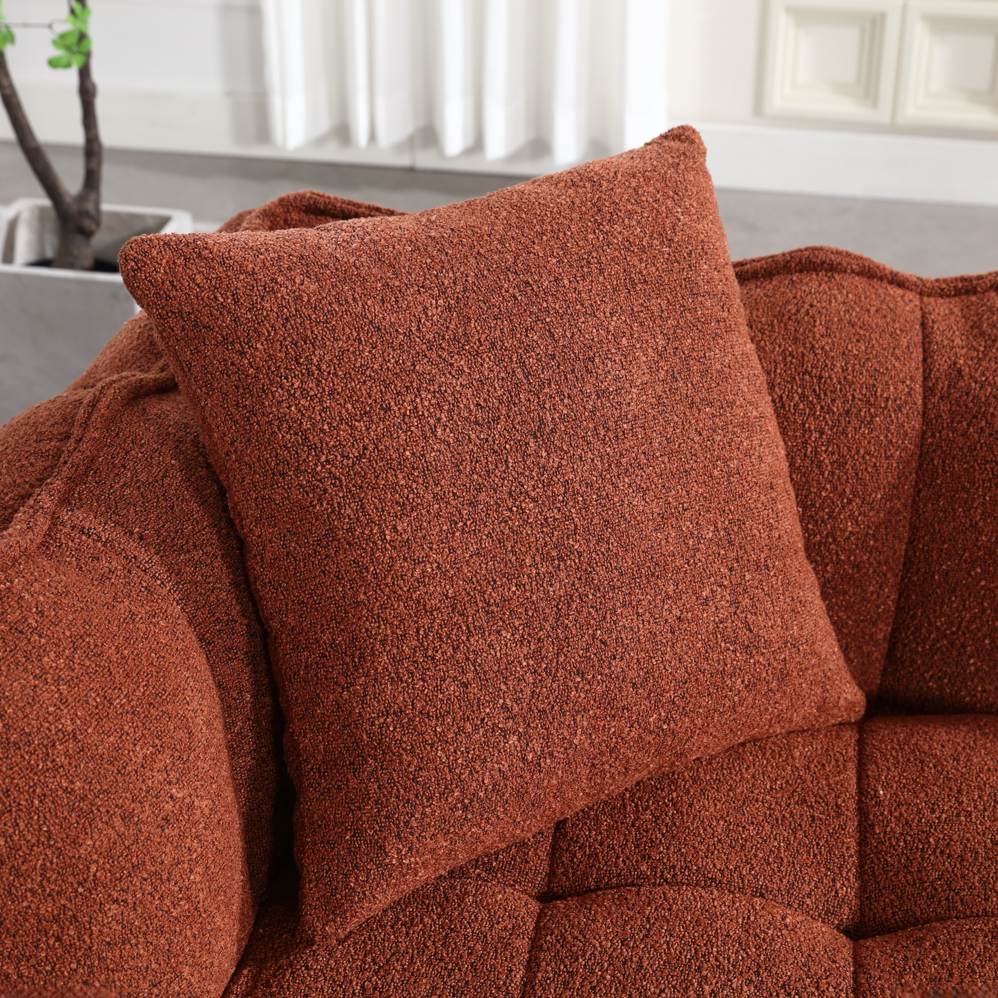 Textured rust boucle throw pillow with tufted sofa detail