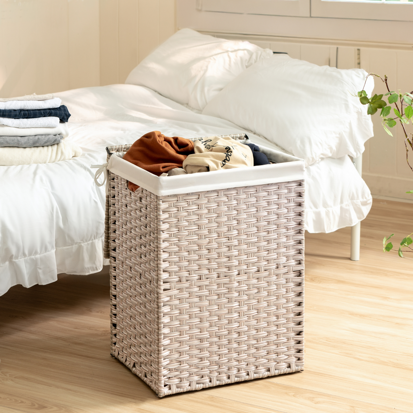 Woven beige rectangular laundry hamper with white liner holding folded clothes