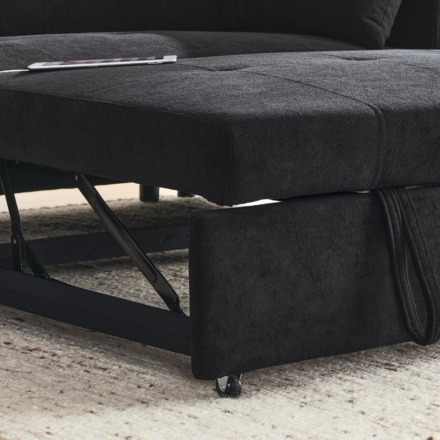 Black fabric sectional sofa with pullout storage compartment and hidden mechanism visible