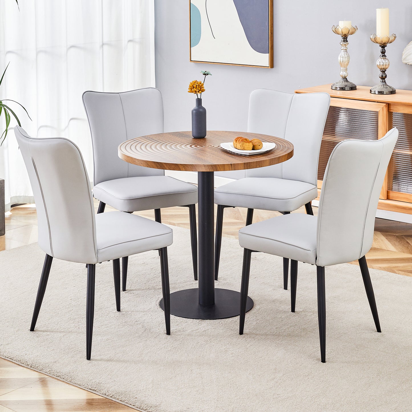 Light grey upholstered dining chairs with black legs around a round wood table
