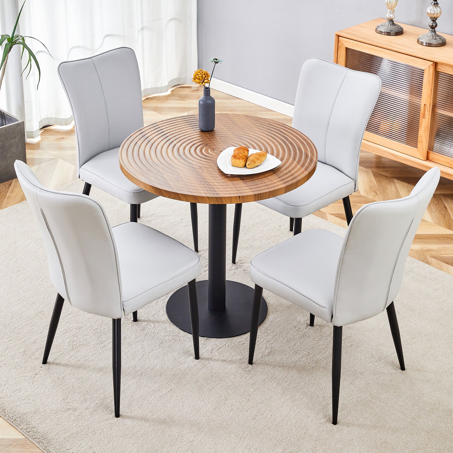 Modern dining set with four light grey faux leather chairs and a round wood table