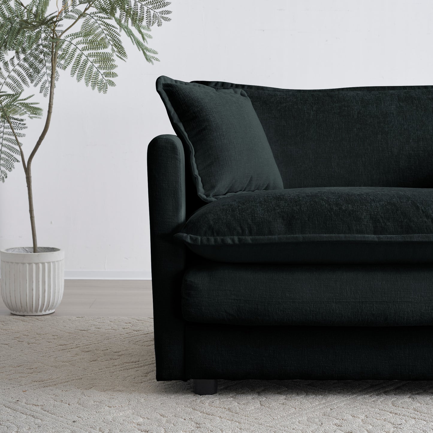 Dark charcoal sofa with plush cushions and a throw pillow on a cream rug