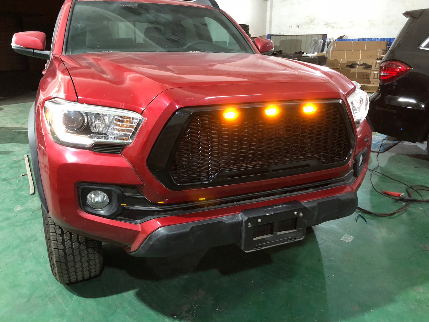 Red Toyota Tacoma truck grill with amber raptor lights installed